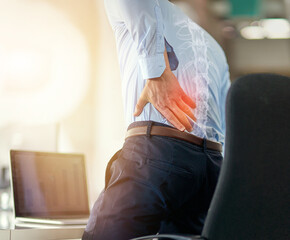 Businessman, back pain and x ray of spine from sitting and working by laptop on desk chair at the...