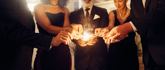 Fire, sparklers and people at a luxury party, event or celebration for new year with formal outfit....