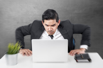 Asian businessman sitting with a laptop on the desk with a shocked expression