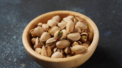 Bowl of whole dry pistachio nuts on wooden table