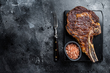Grilled cowboy or rib eye with bone beef steak. Black background. Top view. Copy space