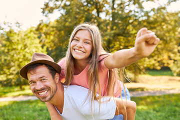 Happy father giving his daughter piggyback ride