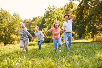 Fototapeta premium Happy family running hand in hand across meadow