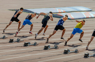 man athletes starting running in 100m sprint race