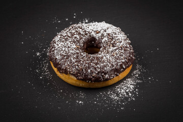 Sprinkling sugar powder on chocolate donut