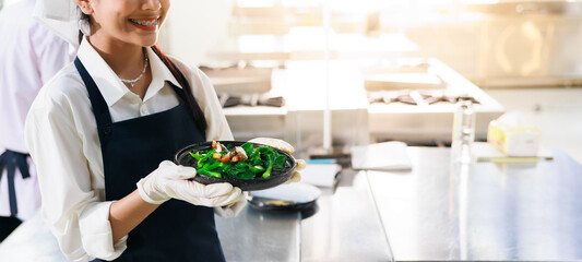 Close up hand holding plate. Cooking class. culinary classroom. group of happy young woman multi - ethnic students are focusing on cooking lessons in a cooking school.