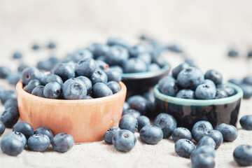 Three ceramic bowls with blueberries and berries scattered around.