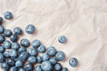 Fresh blueberries scattered on beige craft paper.