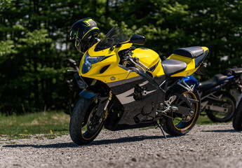 Fototapeta na wymiar Yellow sportbike motorcycle with helmet on the parking in mountains