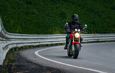 Rider  in black helmet on red classic vintage motorcycle in mountains