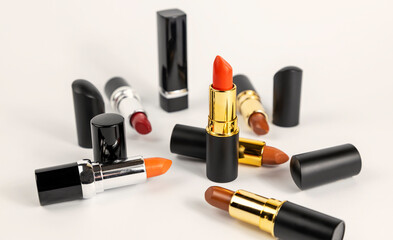 The concept of fashion and beauty. Different shades of lipstick are scattered on a white background.