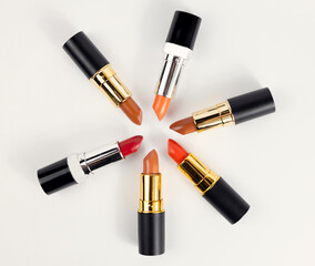 Lipsticks are arranged in a circle, top view on a white background, place for text.