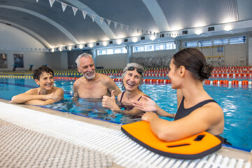 Two seniors talking to their water fitness coach after the class