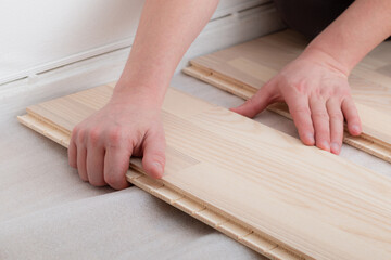 Professional worker installing new parquet flooring indoors, closeup