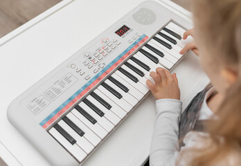 Fototapeta na wymiar The child plays on a beautiful children's synthesizer.
