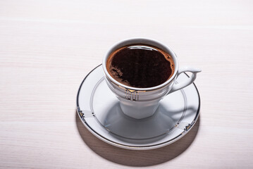 A cup of coffee and saucer on wooden desk.