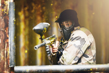 Fototapeta premium Paintball, war and camouflage with a sports man playing a military game for fun or training outdoor. Gun, soldier and target with a male athlete shooting a weapon outside during an army exercise
