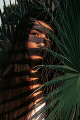 Close-up portrait of a girl among palm leaves.