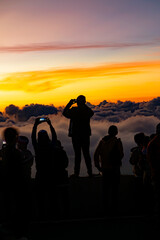 Fototapeta premium Silhouette person group watching floating sea of clouds,Sea of fog, Sky above clouds,taking cloudscape photos with mobile phones in the morning,sun rising,travel long weekend,Inthanon mountain.