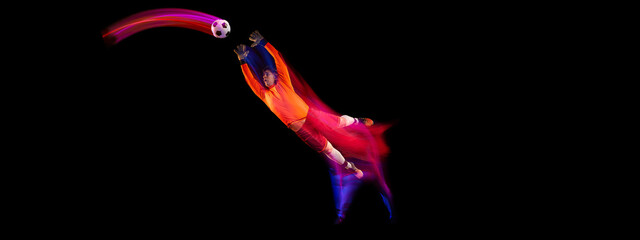 Sportive energetic man, soccer football goalkeeper in action, motion over dark background with mixed neon light. Concept of sport, achievement, competition, goals.