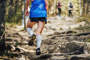 male runner in compression calf sleeve run over rocks © Real Sports Photos