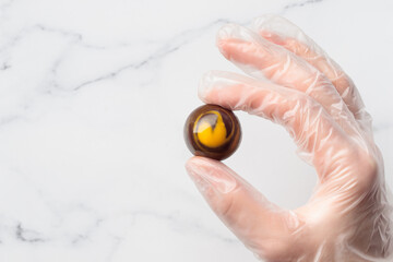 Painted handcrafted chocolate bonbon in a human hand