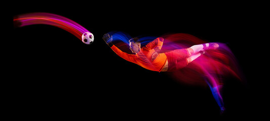 Sportive energetic man, soccer football goalkeeper in action, motion over dark background with...
