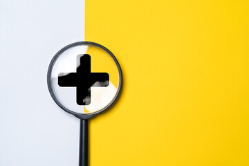 Black  plus sign inside of magnifier glass on yellow and white background for focus positive thinking mindset of personal development benefit and health insurance concept .