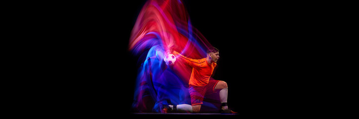 Sportive energetic man, soccer football goalkeeper in action, motion over dark background with...