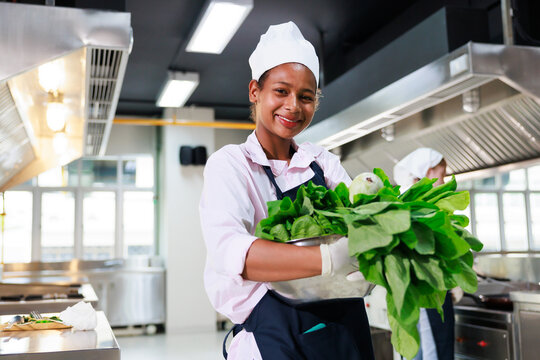 portrait young teen girl cook student. Cooking class. culinary classroom. happy young african woman students holding fresh vegetables for cooking in cooking school.