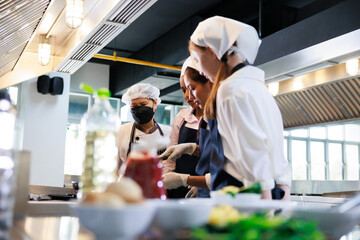 Senior asian woman chef teach student. Cooking class. culinary classroom. group of happy young woman multi-ethnic students are focusing on cooking lessons in a cooking school.