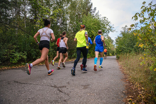 group male and female athletes running marathon race in park