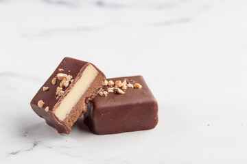 Chocolate bonbons with praline on white marble background