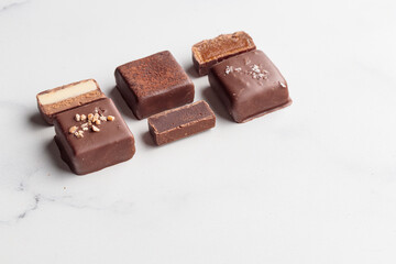 Chocolate bonbons with praline on white marble background