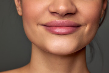 Cropped image of female face, lips, nose, chin on grey studio background. Lip augmentation, face...