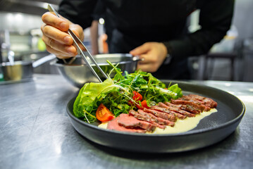chef hand preparing Roastbeef salad with vegetables on restaurant kitchen