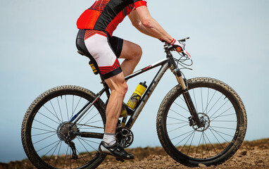 Fototapeta premium close-up male athlete mountain biker in background sky