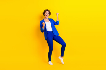 Fototapeta na wymiar Full length photo of shiny lucky woman wear blue jacket screaming rising fists isolated yellow color background