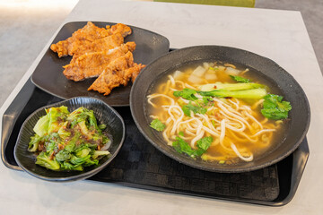 Close up shot of deep fried pork chop with noodle and vegetable