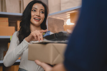 credit card and wireless POS terminal for card payment concept, Young Asian girl with a credit card received a parcel from a male delivery man The woman paid the male delivery man