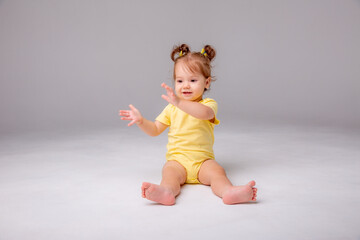 baby girl with yellow bodysuit sitting on a white background