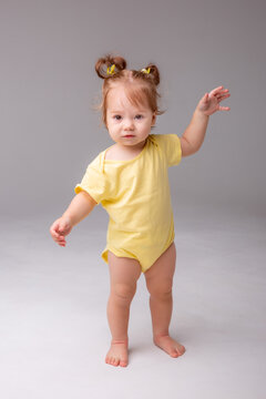 Baby Girl Starting To Walk Takes Her First Steps On A White Background