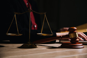 Justice and law concept.Male judge in a courtroom with the gavel, working with, computer and docking keyboard, eyeglasses, on table in morning light