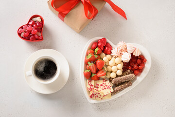 Charcuterie Valentines Day sweet board with coffee, chocolate sweets, strawberries, candies and gift on white background. Top view.