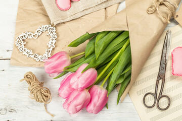 Bouquet of fresh pink tulips. Making spring floral decorations. Tools, vintage scissors, craft paper