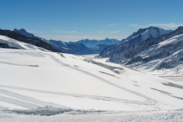 Fototapeta na wymiar Snow plow tracks cross a frozen alpine landscape at Jungfraujoch