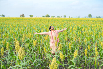 wide full shot of Happy smiling young farmer showing grown crop by felling at farmland - concept of...
