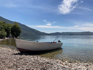 boat with motor on lake coast in background sky and mountains