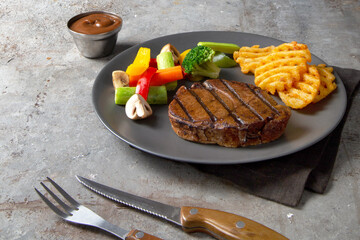 a piece of steak served with fried potato, vegetable, and brown sauce on a plate