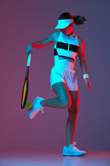 Studio shot of active professional tennis player training with tennis racket over gradient...